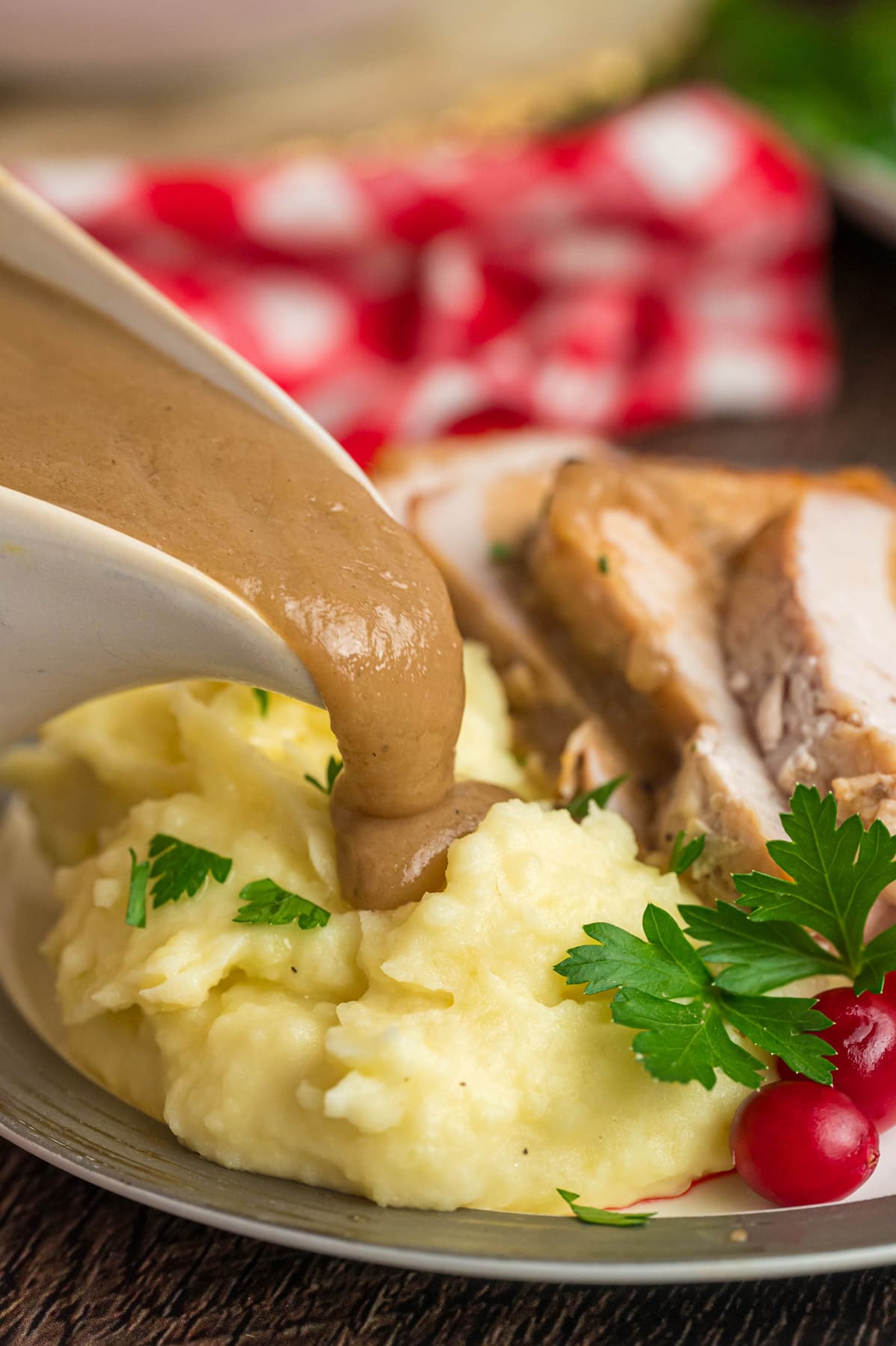 Gravy being poured over mashed potatoes on a plate with slices of turkey