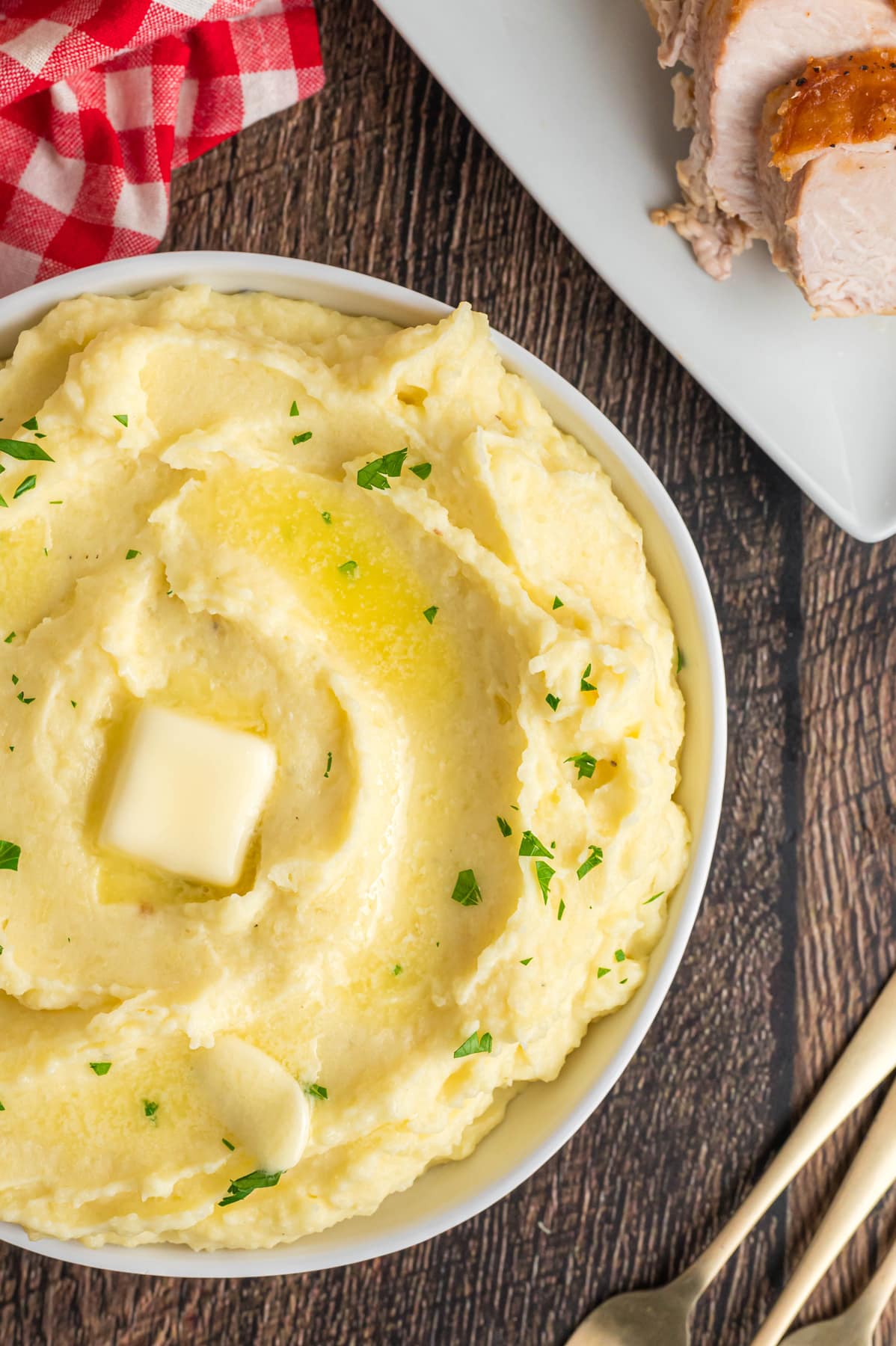 A white bowl of creamy mashed potatoes with butter on top
