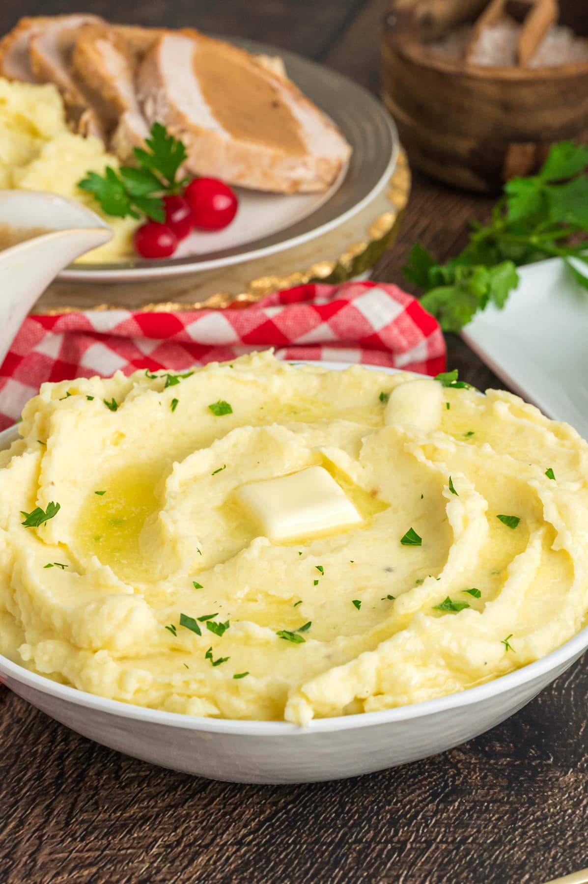 Angled view of a bowl of creamy mashed potatoes topped with a dab of butter