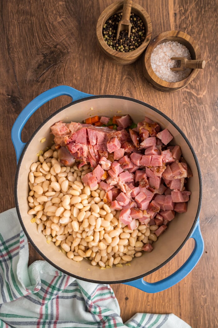 Diced ham and soaked white beans added to a pot to make Ham and Bean Soup.