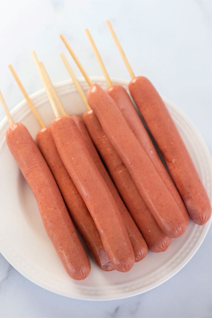 hotdogs with skewers all ready to be made into corndogs