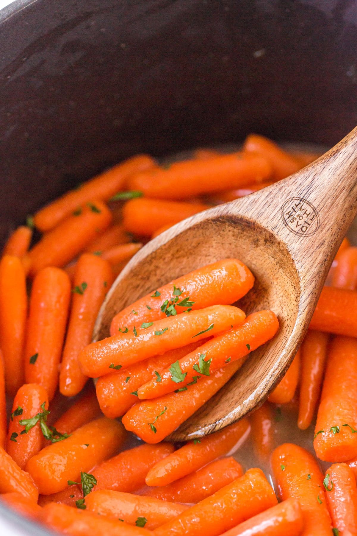 Wooden spoon lifting up some of the carrots.