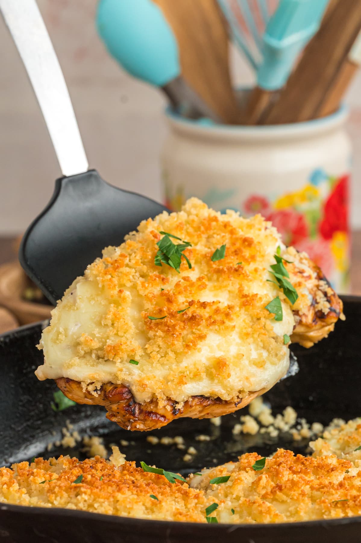 A black spatula serving a piece of parmesan crusted chicken