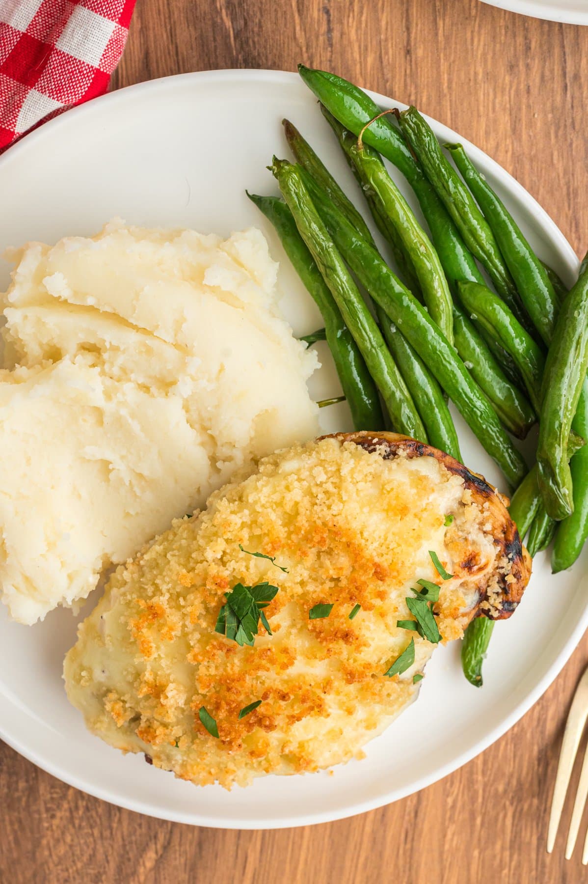 Parmesan crusted chicken on a plate with mashed potatoes and green beans