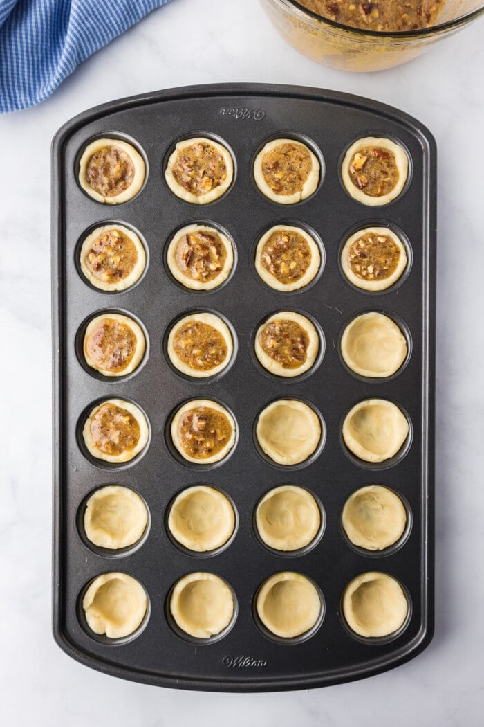 A mini muffin pan with pecan tassies.
