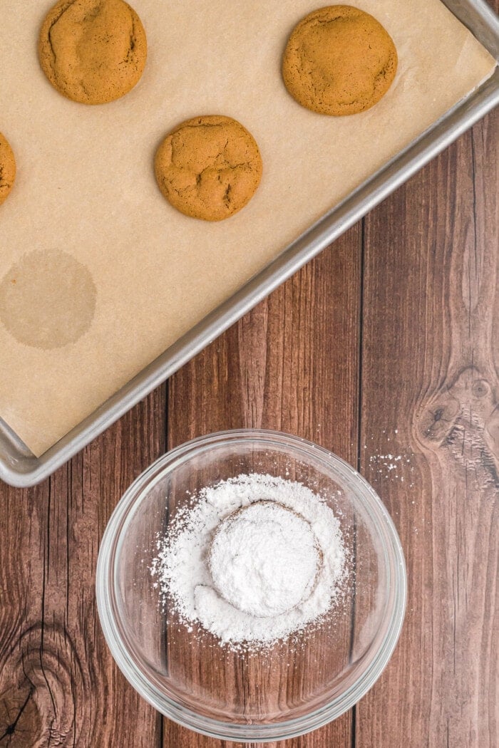 Adding powdered sugar to a Pfeffernusse cookie.