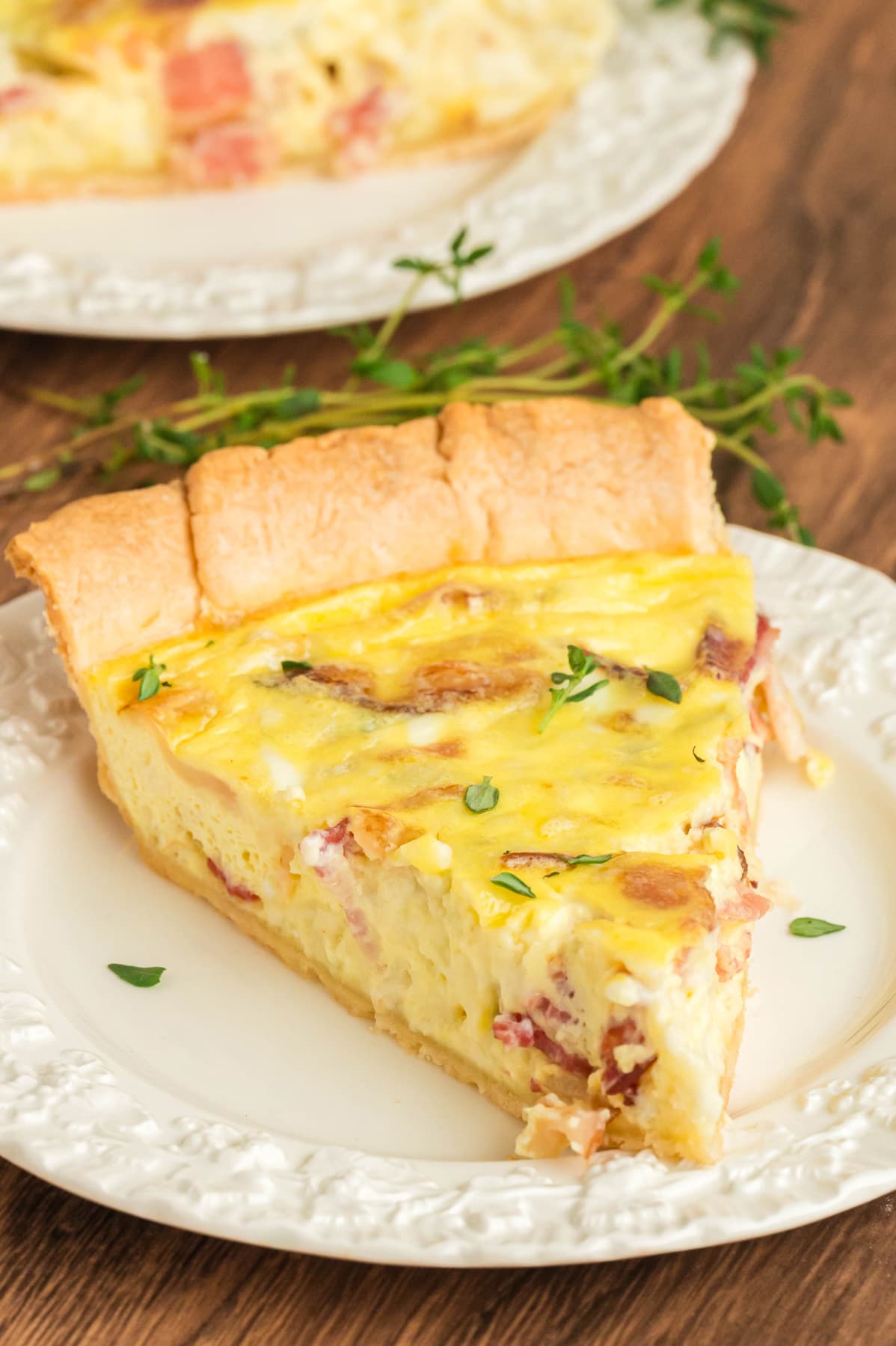 A slice of bacon quiche on a white plate