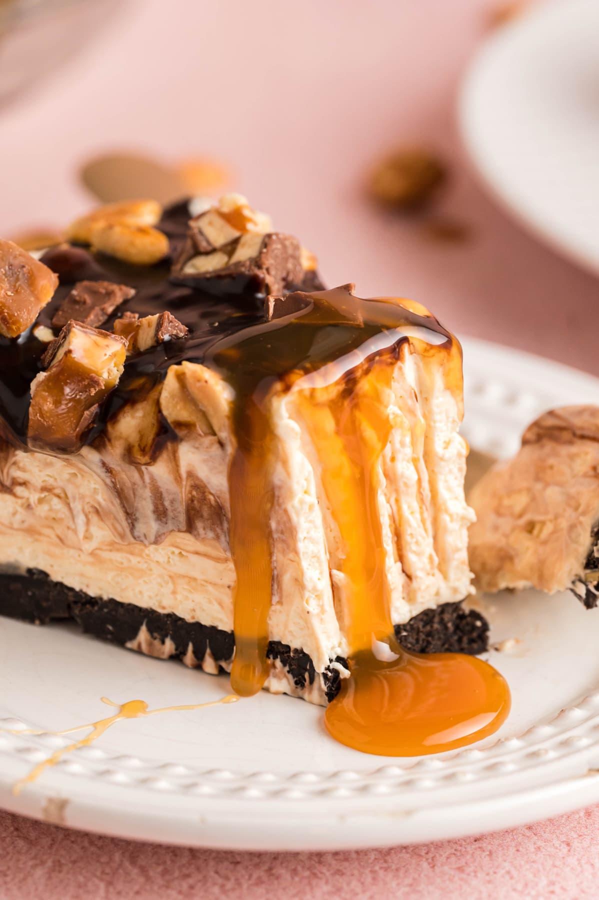 A slice of Snickers Pie with caramel sauce dripping down the sides.