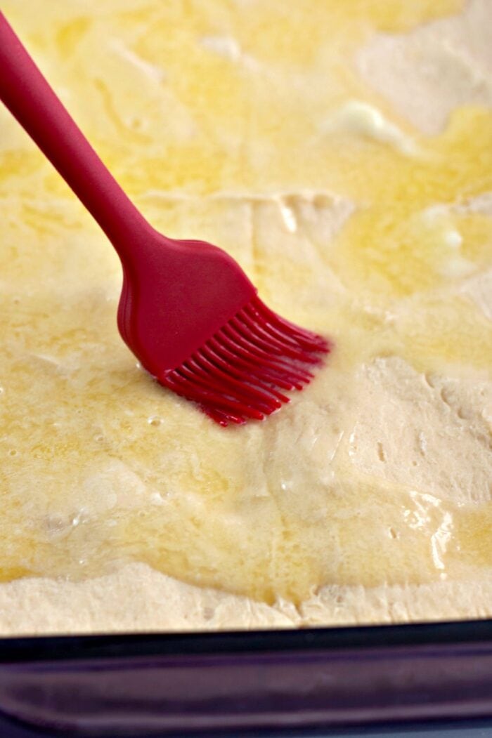brushing melted butter over top of the crescent rolls