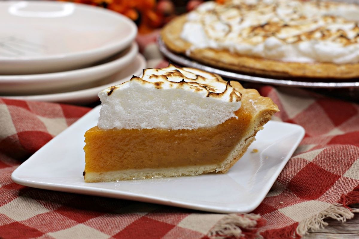 A slice of the Sweet Potato Pie Recipe with Marshmallow Meringue on a patterned cloth.