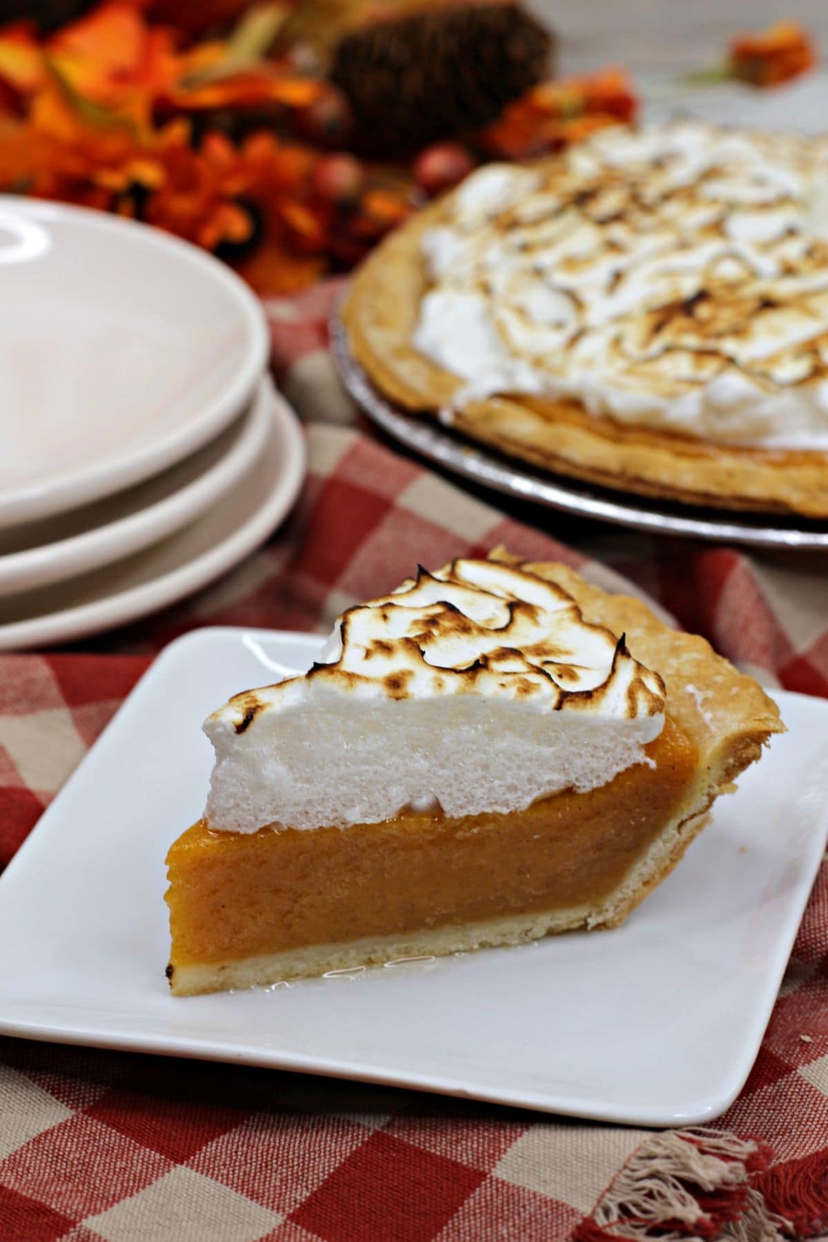 A slice of the Sweet Potato Pie Recipe with Marshmallow Meringue on a patterned cloth.