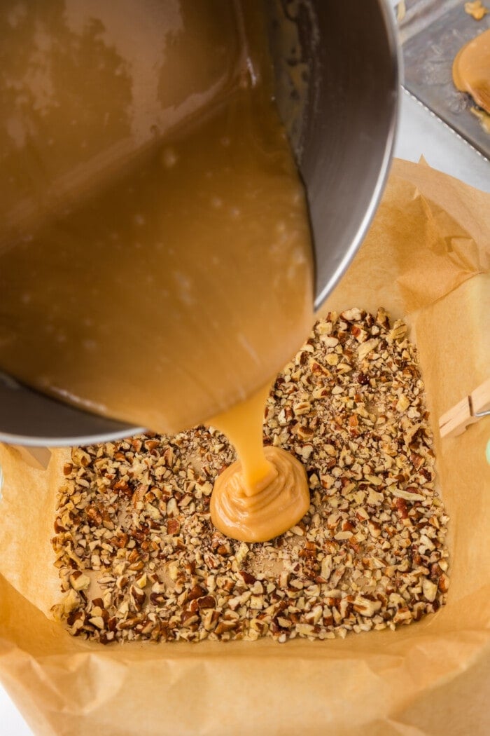 Pouring caramel over chopped pecans.