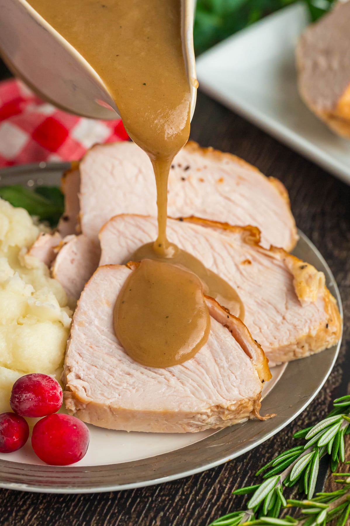 Gravy from drippings being poured over sliced turkey