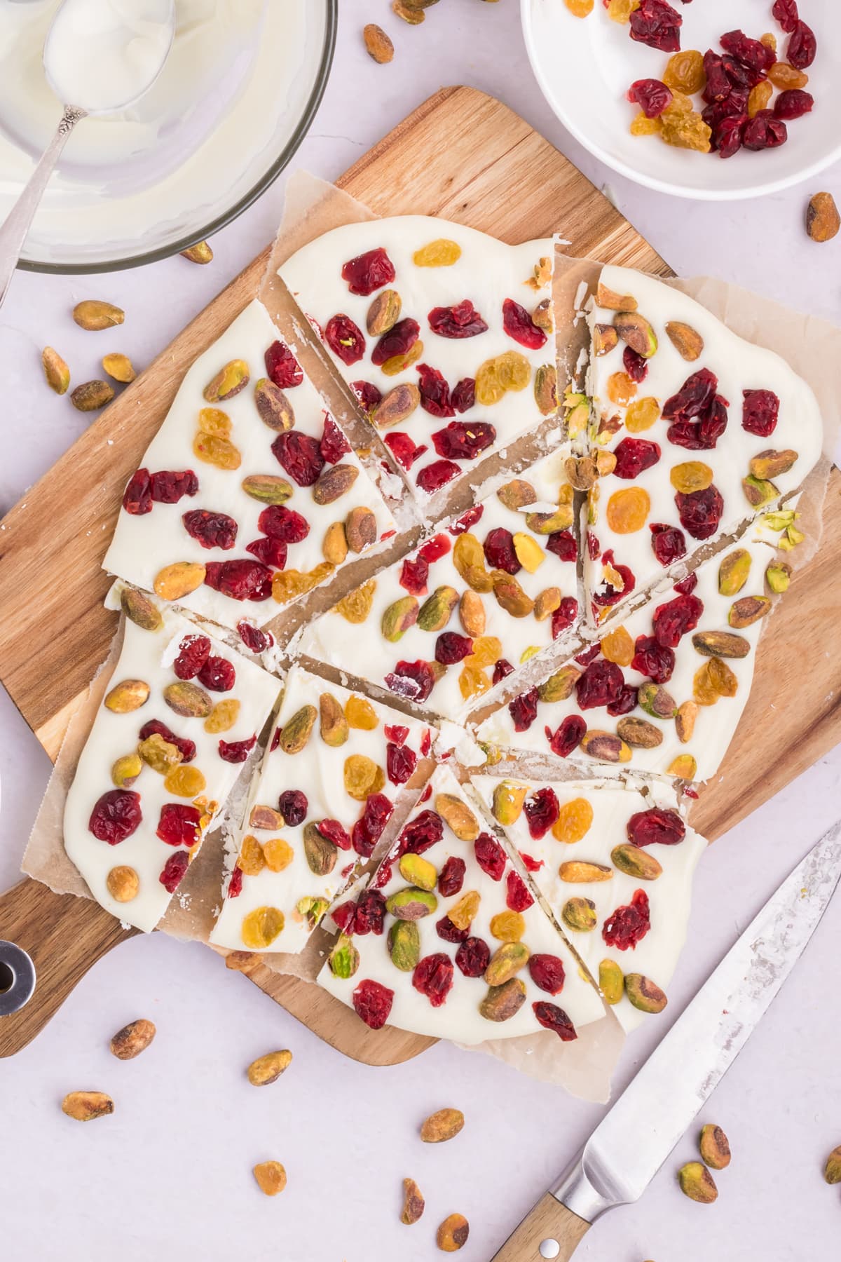 Pieces of cranberry pistachio bark on a wood cutting board.