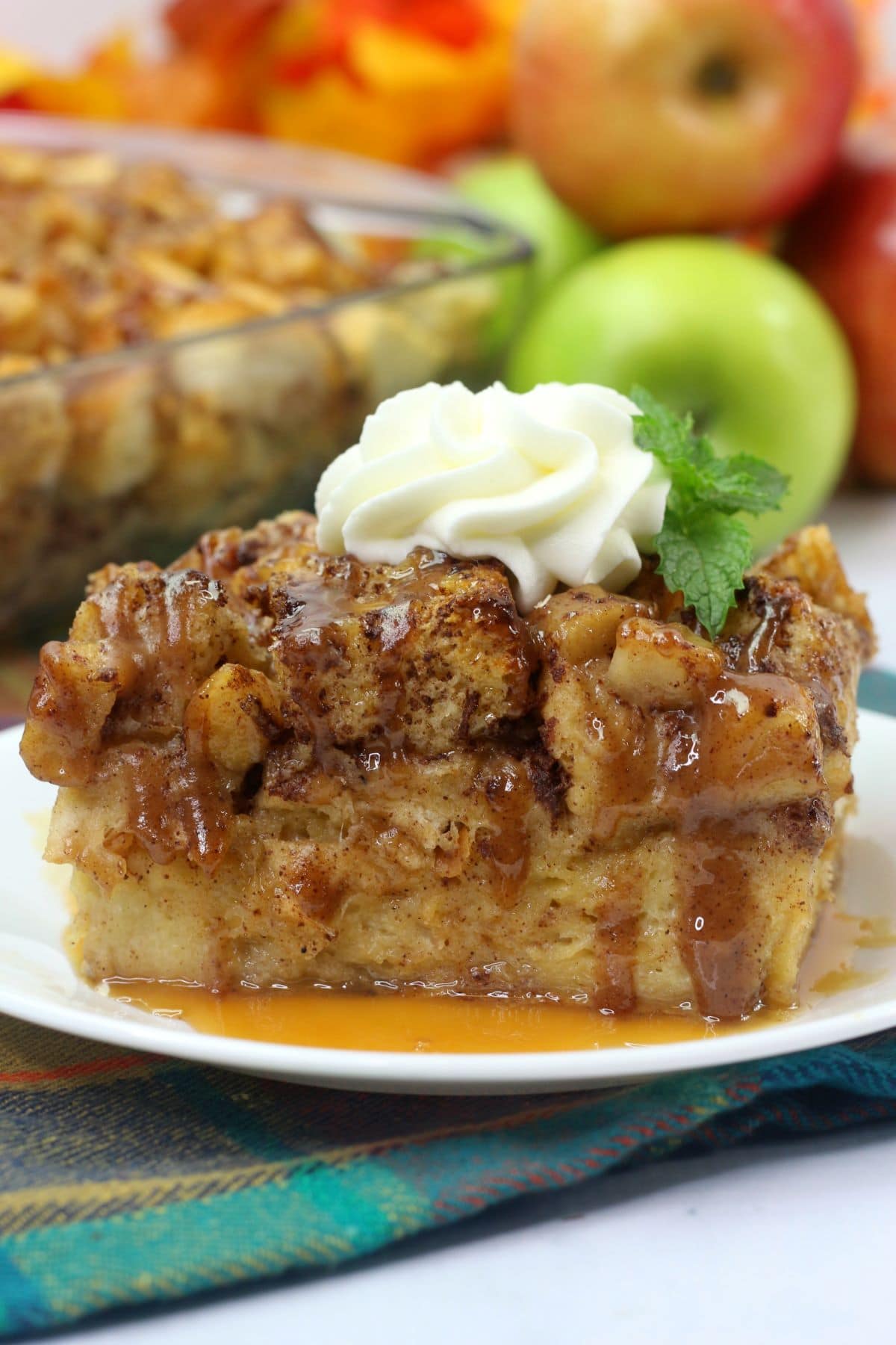 Apple bread pudding with whipped cream on top on a white plate