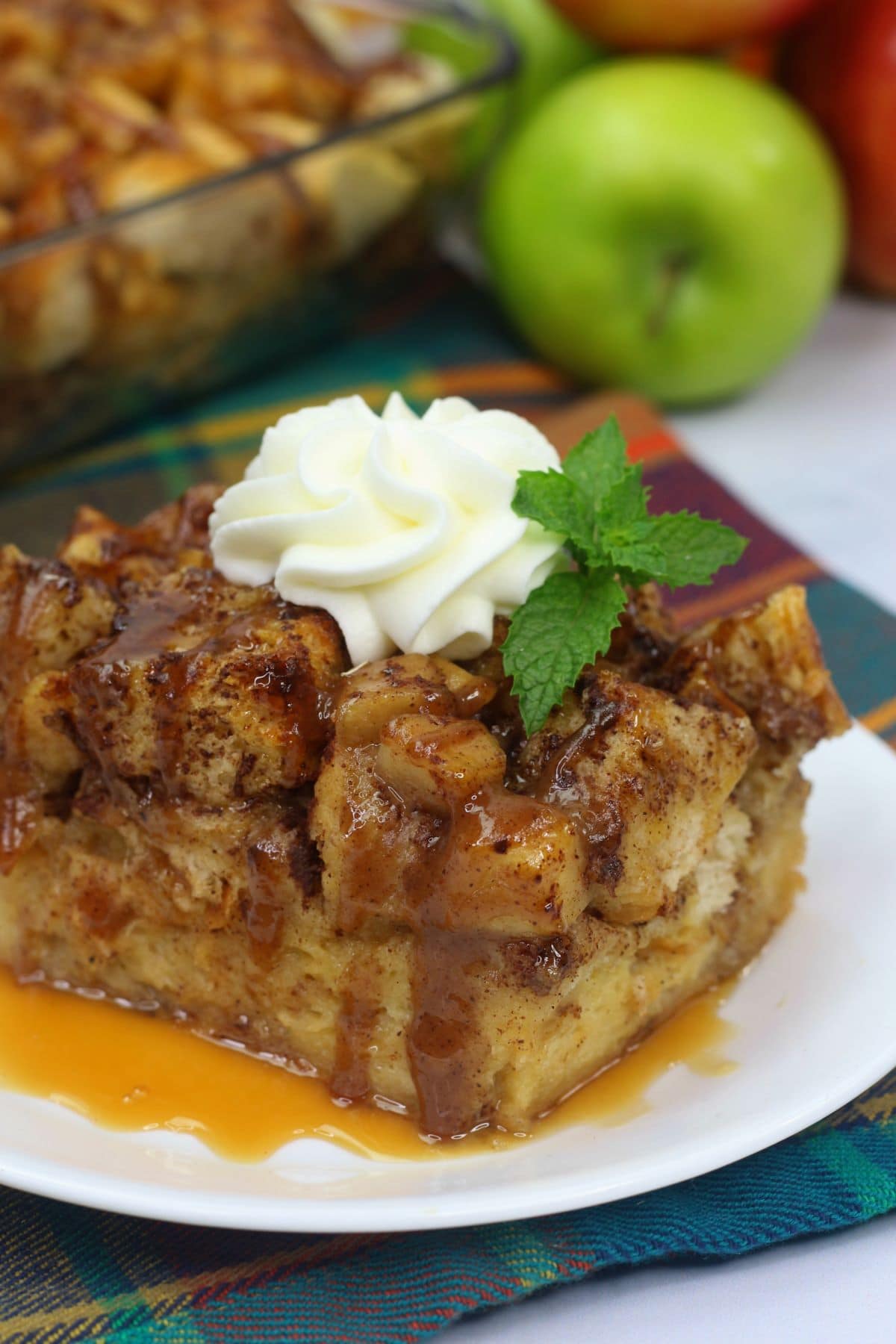 Apple bread pudding with whipped cream on top on a white plate