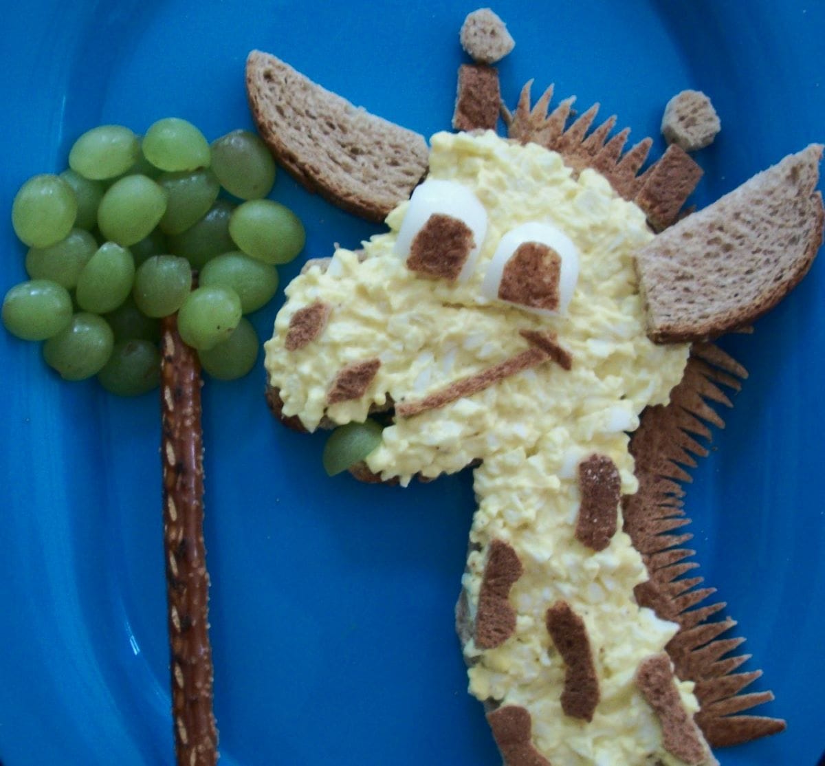 giraffe lunch with an open faced egg salad sandwich that looks like a griffe on a blue plate