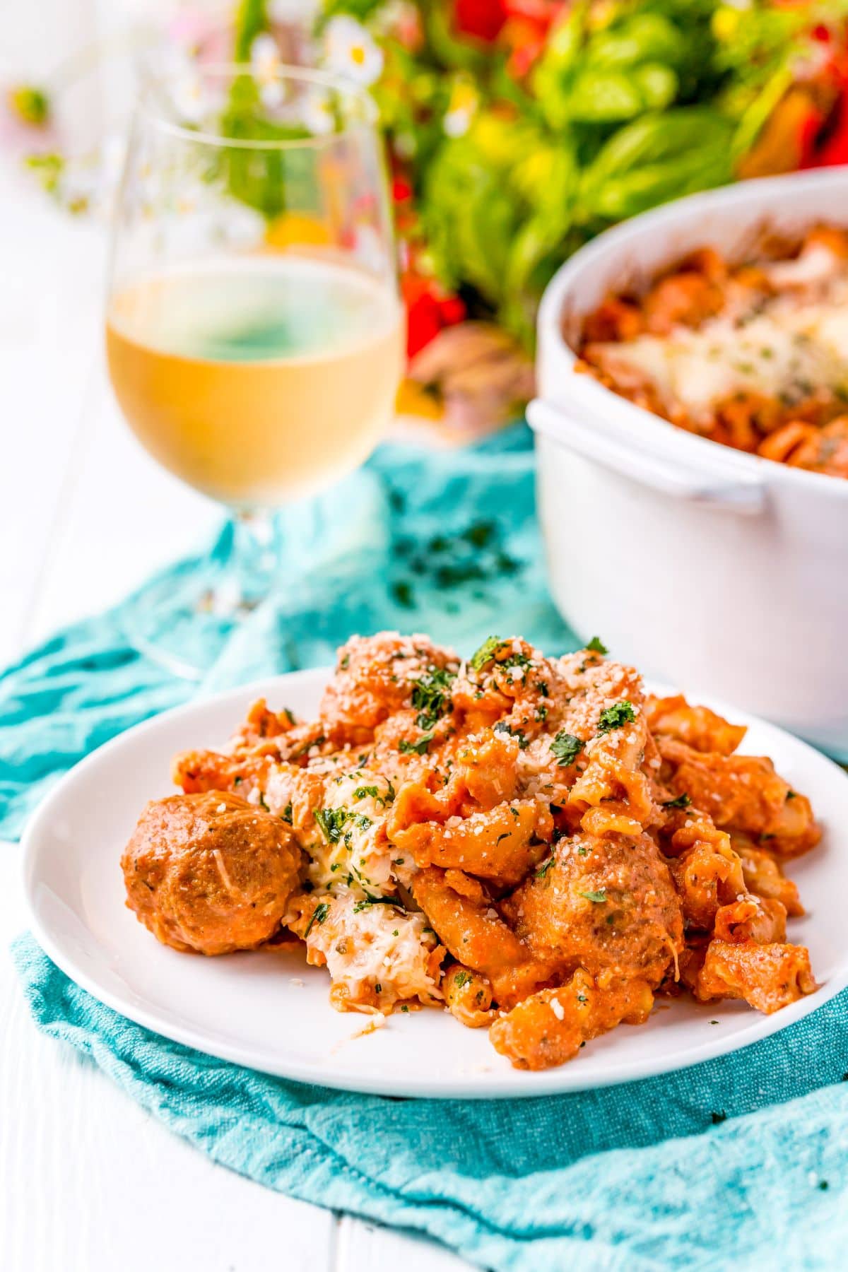Meatball Pasta Bake on  plate with a glass of wine in the background