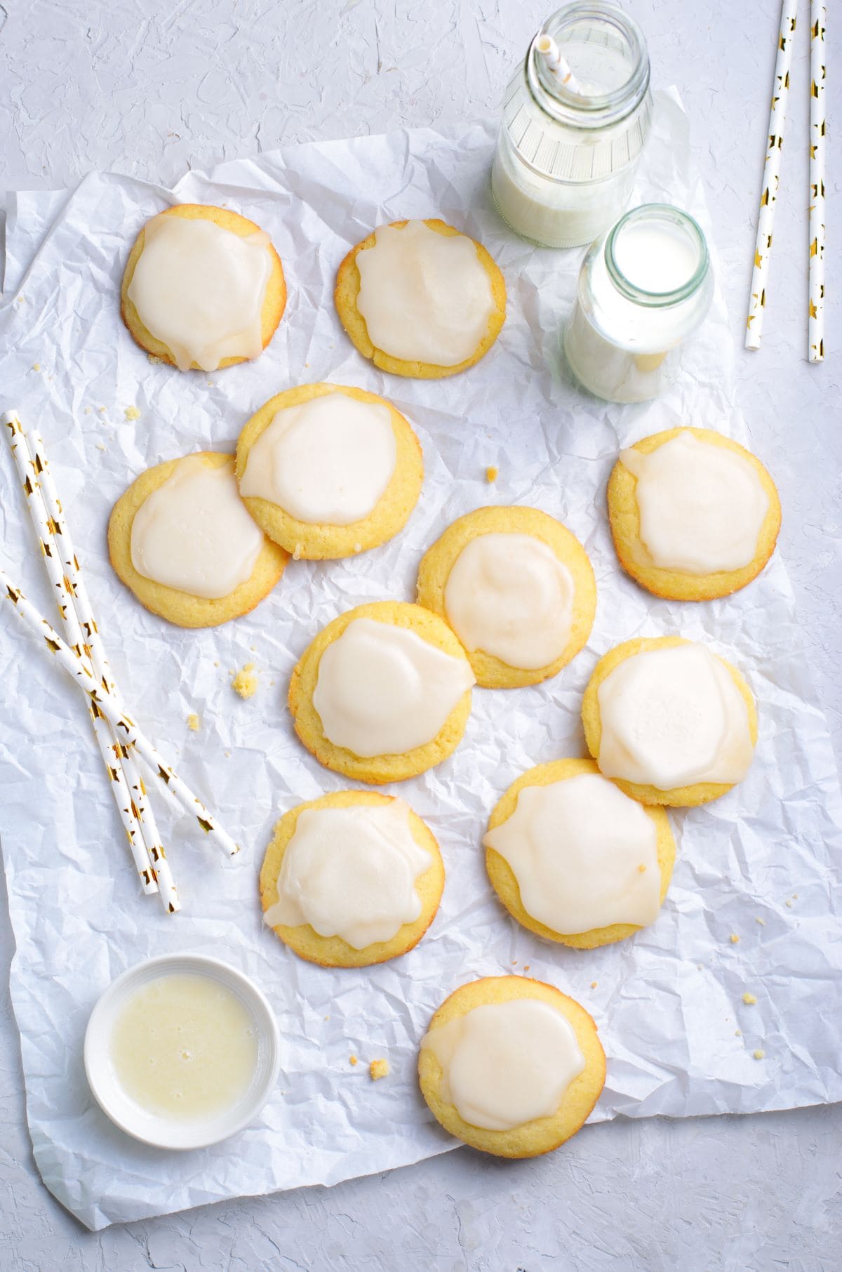 Vanilla Meltaway Cookies on parchment paper with straws and milk