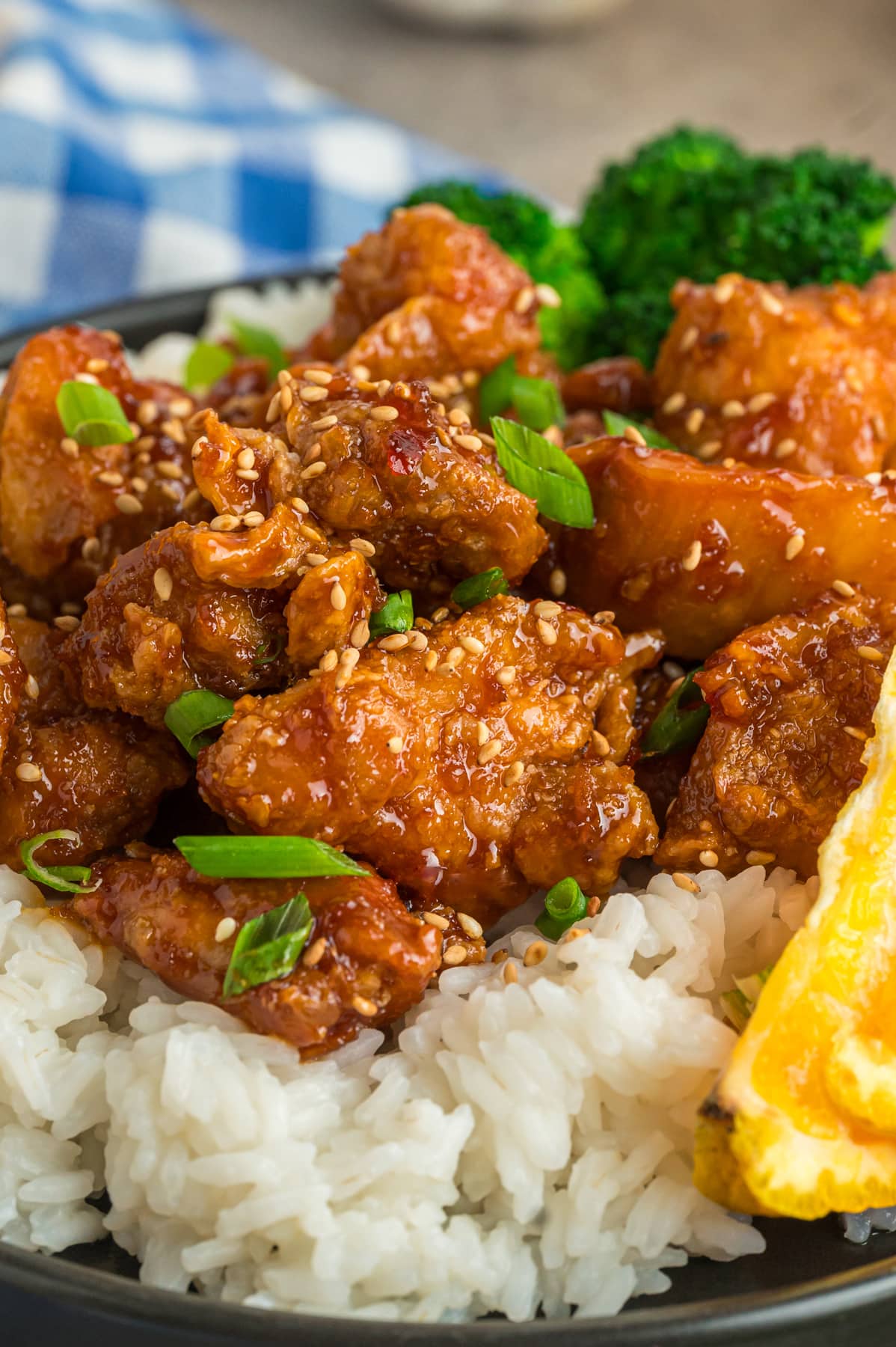 Orange chicken garnished with green onions on top of white rice.