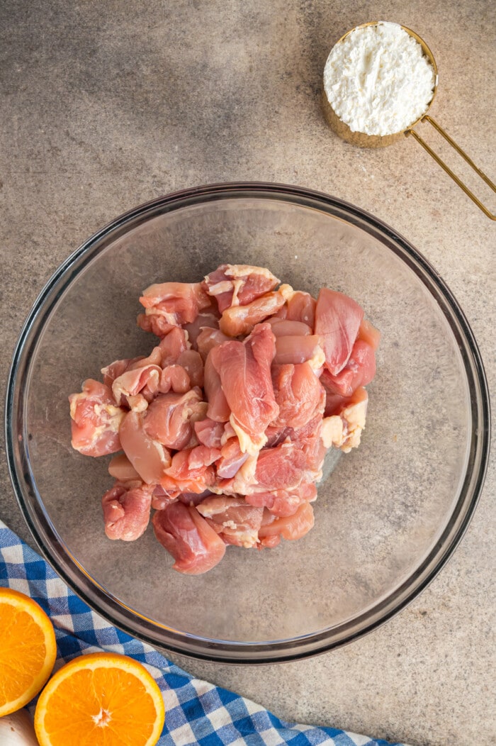 Chicken thighs cut into bite size pieces in a clear bowl.