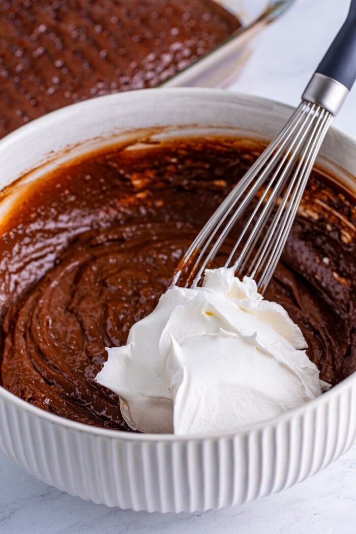 Combining the cool whip into the chocolate for the topping for a Better Than Anything Cake.