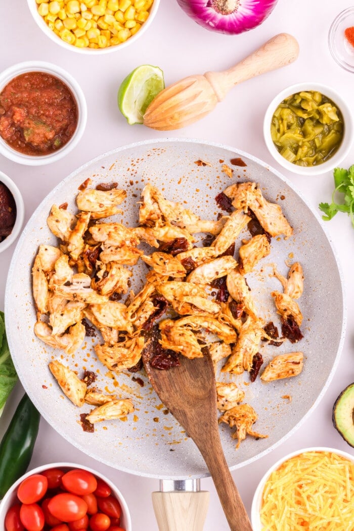 Shredded chicken with Mexican spices in a white bowl to be added to a burrito bowl recipe