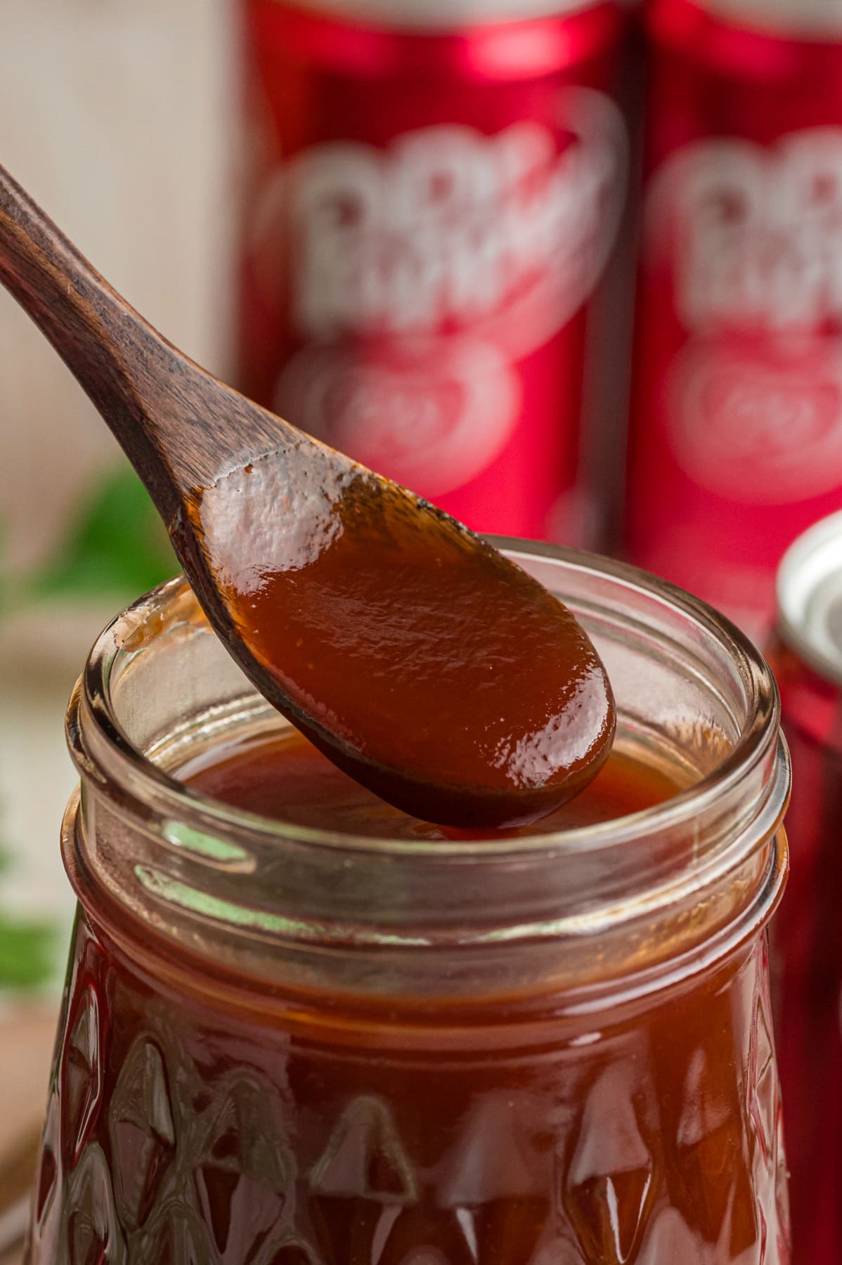 A wooden spoon in a jar of Dr Pepper BBQ Sauce