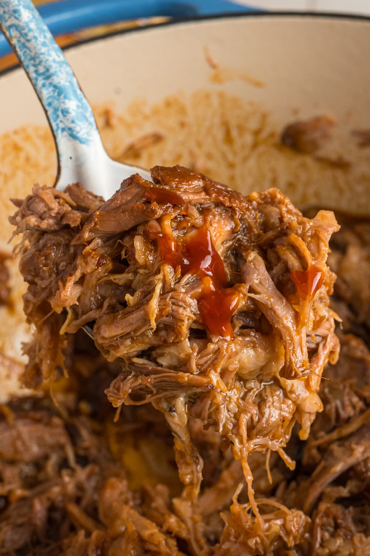 A spoonful of Dr Pepper pulled pork over the pan