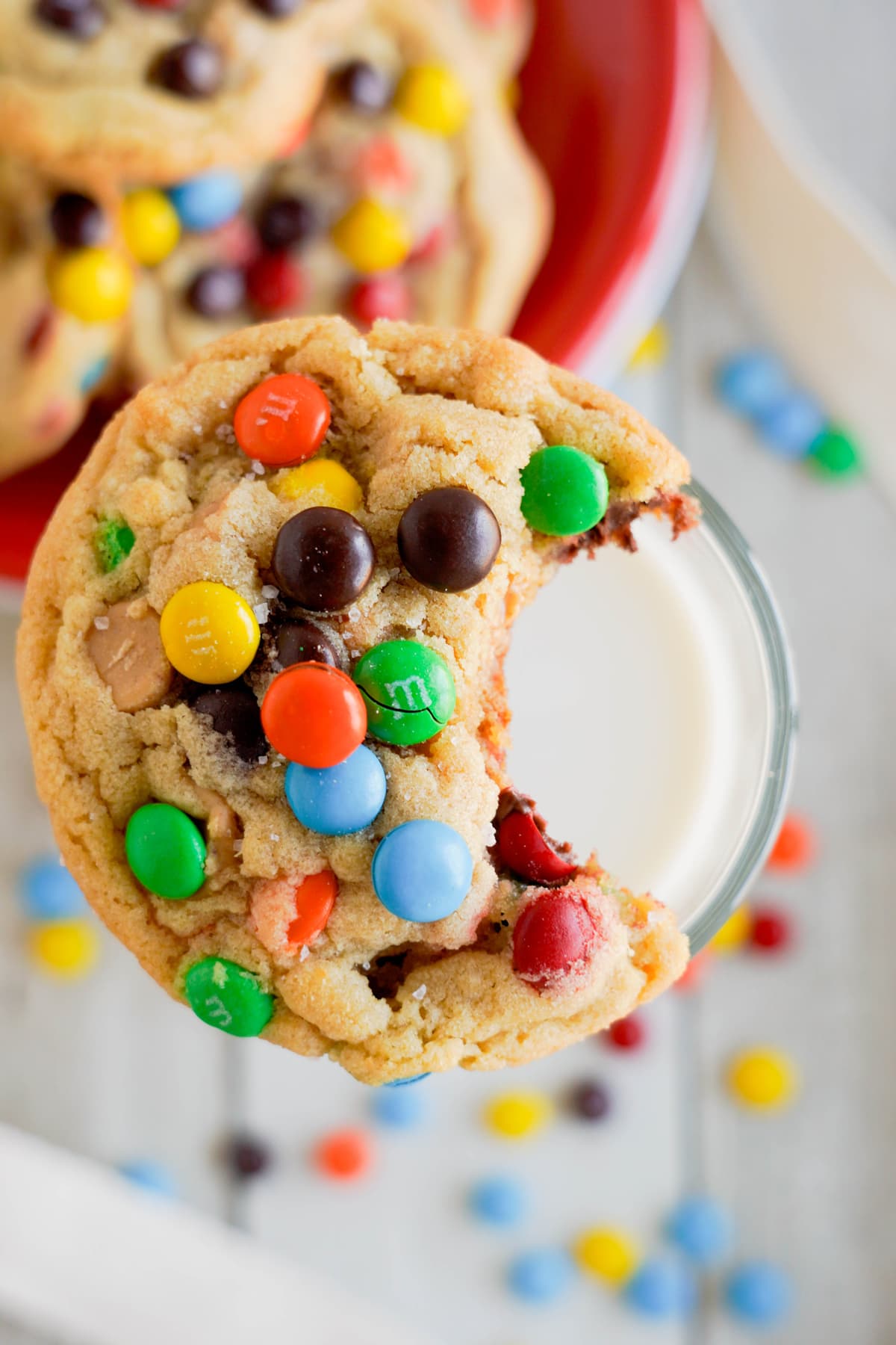 Peanut Butter M&M cookie with a bite out of it sets on a glass of milk.