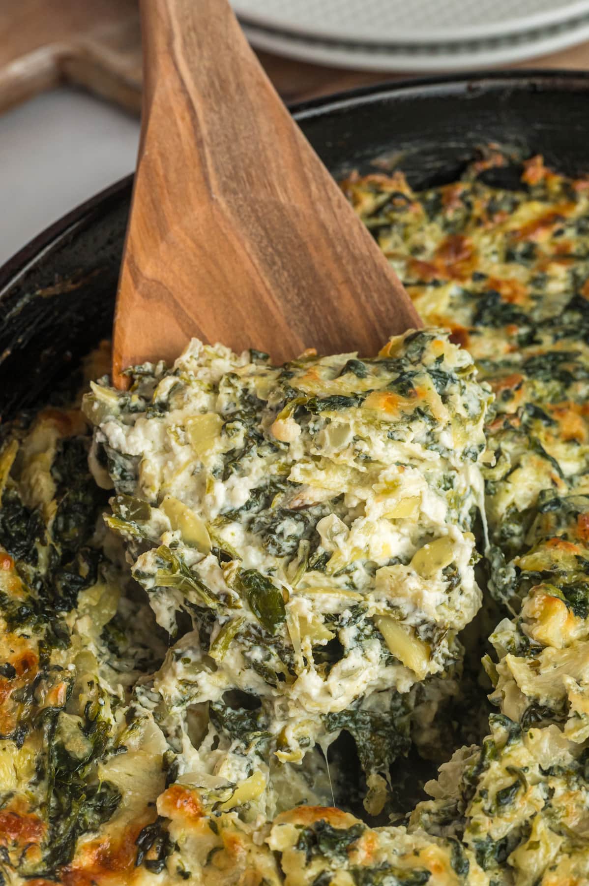 Hot Spinach Artichoke Dip spooned from a cast iron skillet.