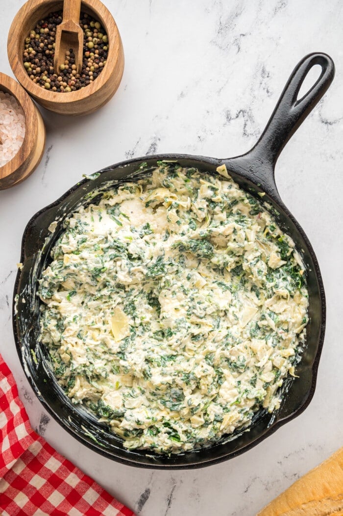 Spinach Artichoke Dip in a cast iron skillet before cooking.