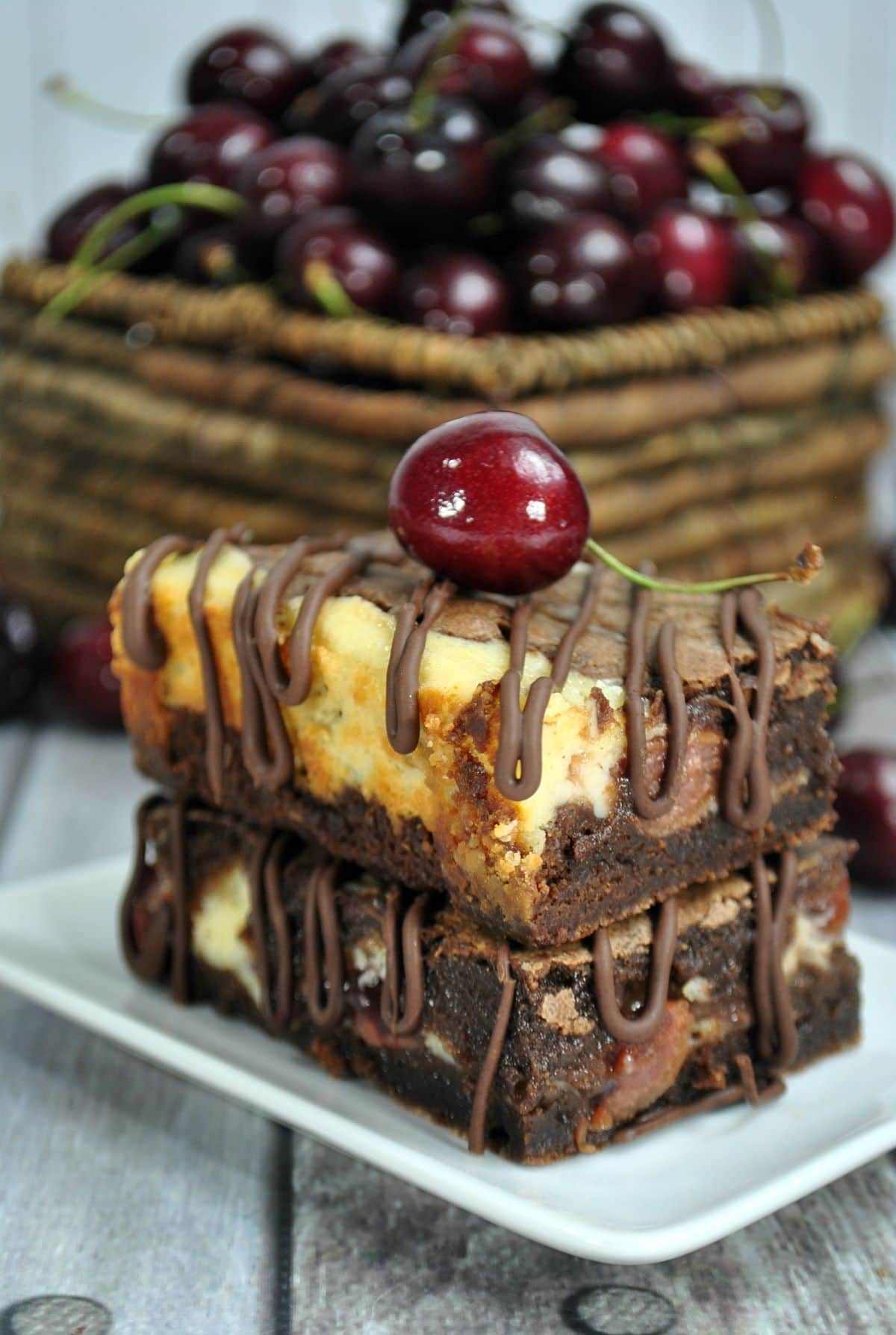 Cherry Pie Brownie Cheesecake Bars with a cherry on top on a plate