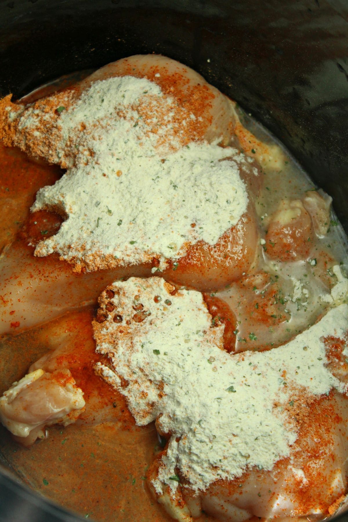 raw chicken and seasoning in a slow cooker