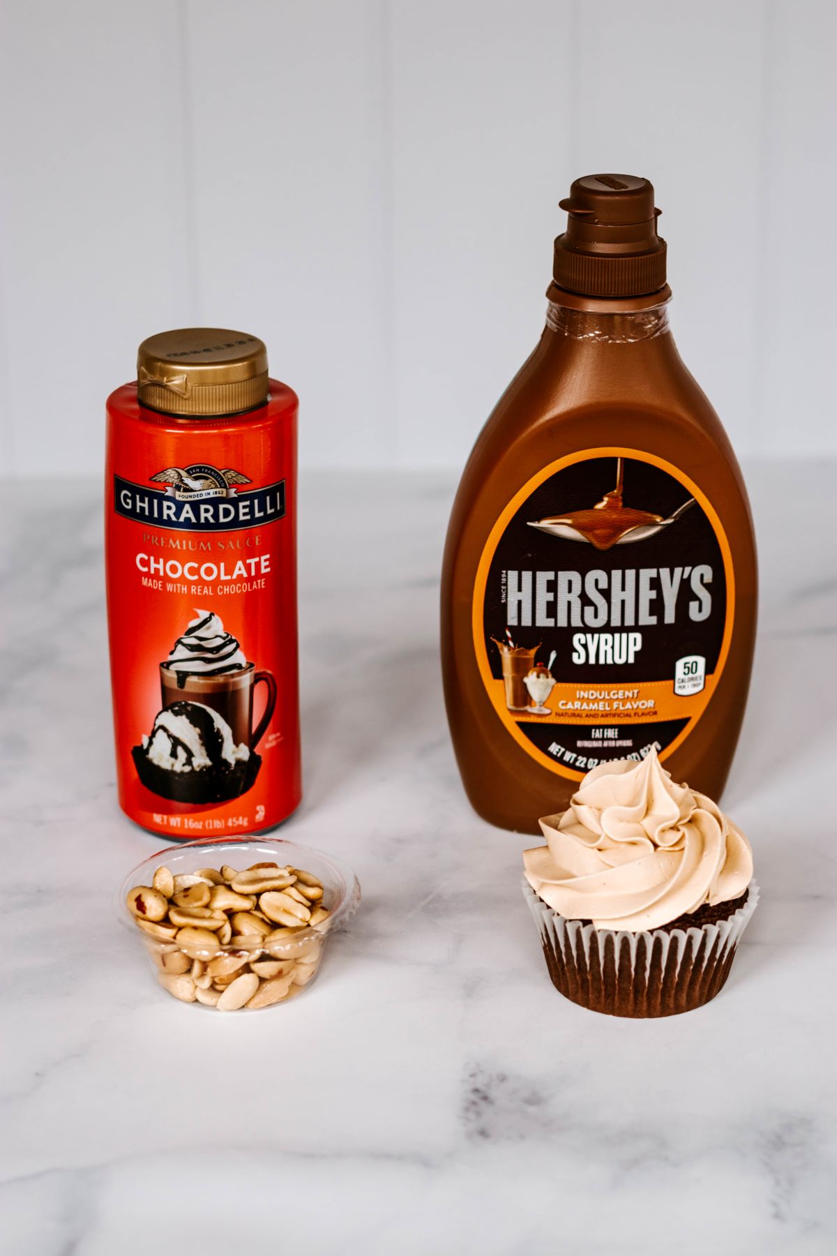 chocolate and caramel syrup with peanuts and a frosted cupcake