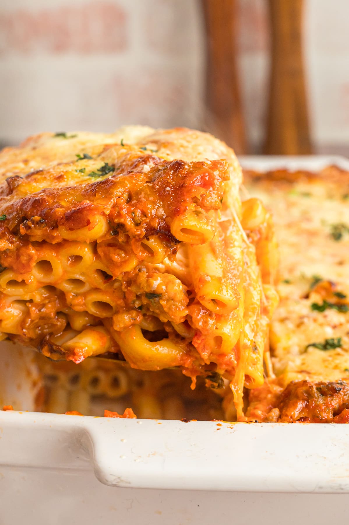 A portion of baked ziti being served from the pan