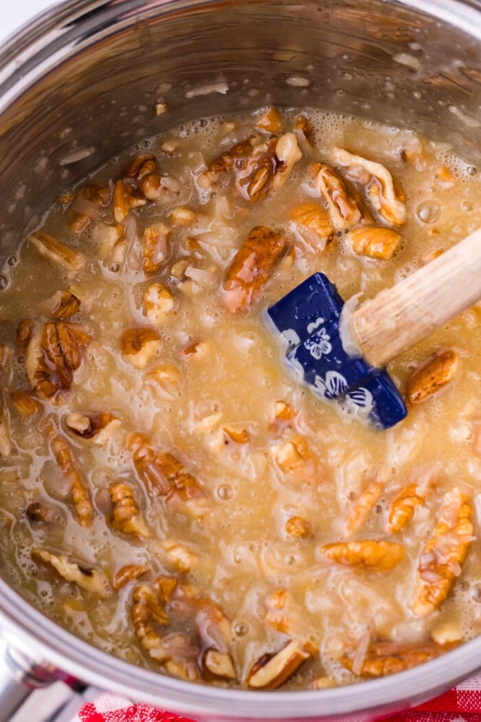 A spatula stirring the pecan coconut mixture for German chocolate cake