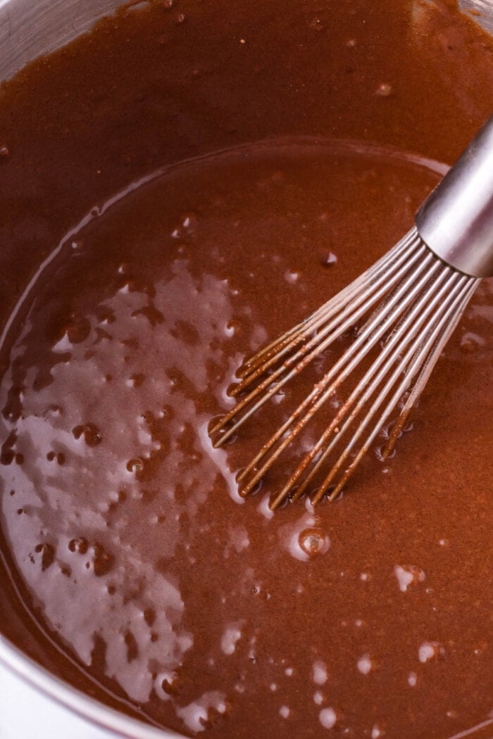 A whisk stirring chocolate cake batter