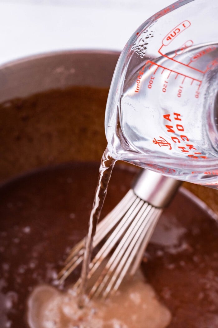 Hot water being whisked into chocolate cake batter