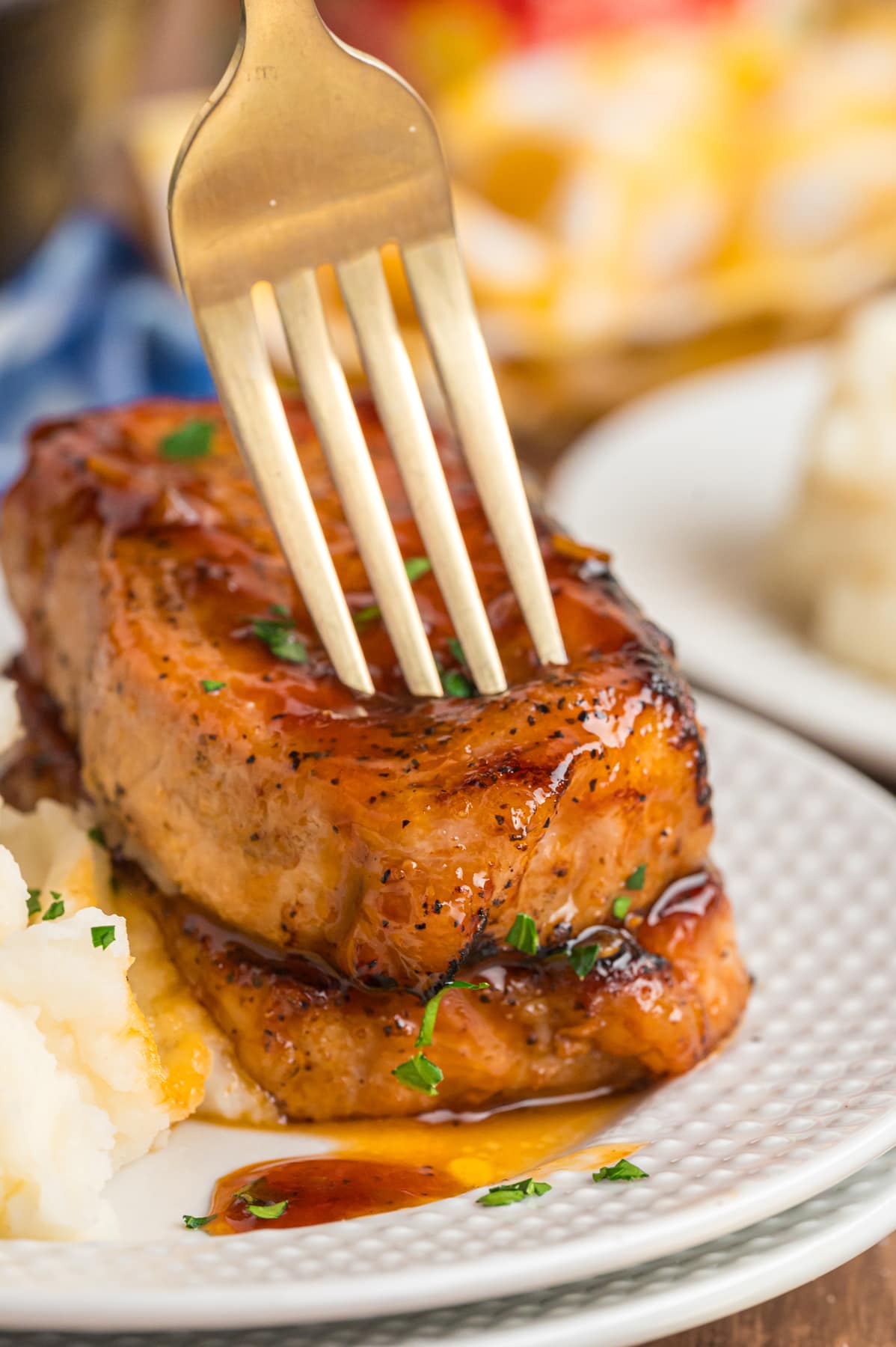A fork in the top of two honey garlic pork chops