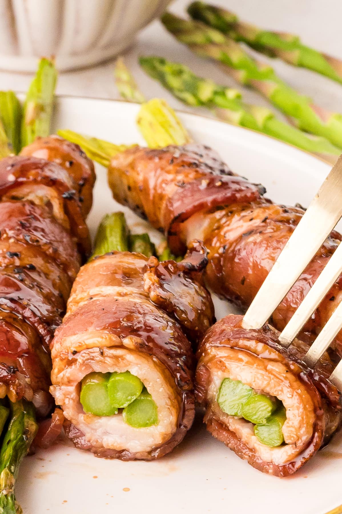 A fork in a piece of bacon wrapped asparagus, to show the inside of the bundle