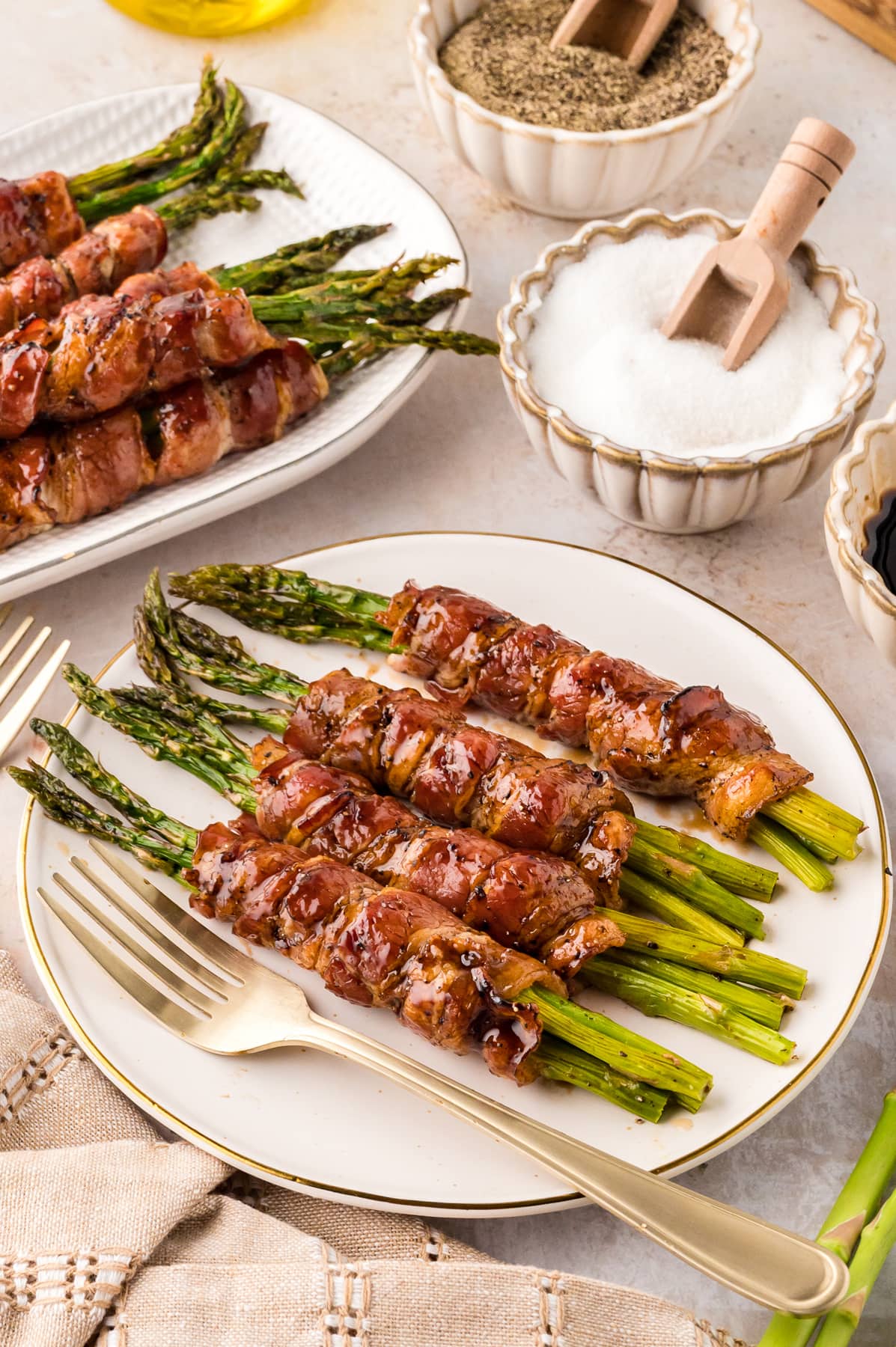 Four bundles of bacon wrapped asparagus on a white plate