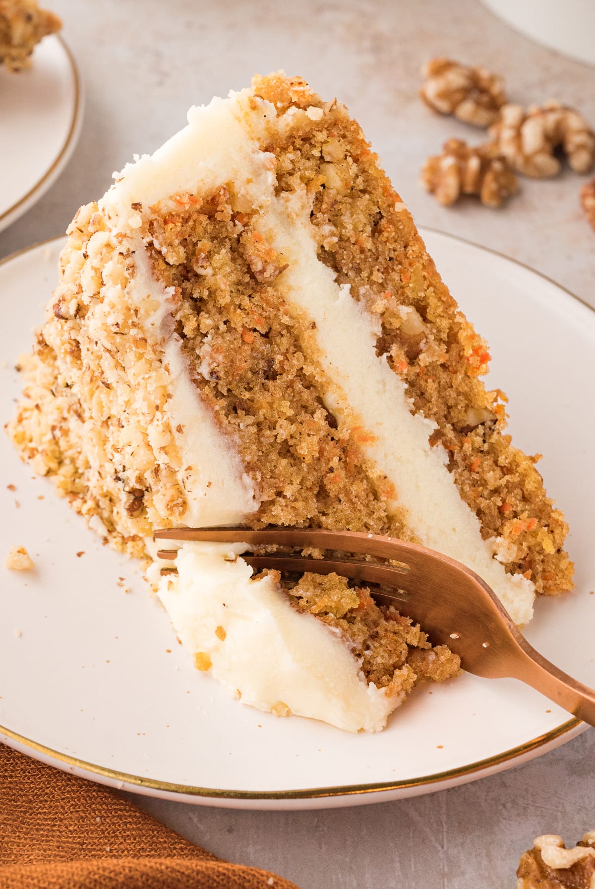 A fork diving into a slice of the best carrot cake recipe on a white plate