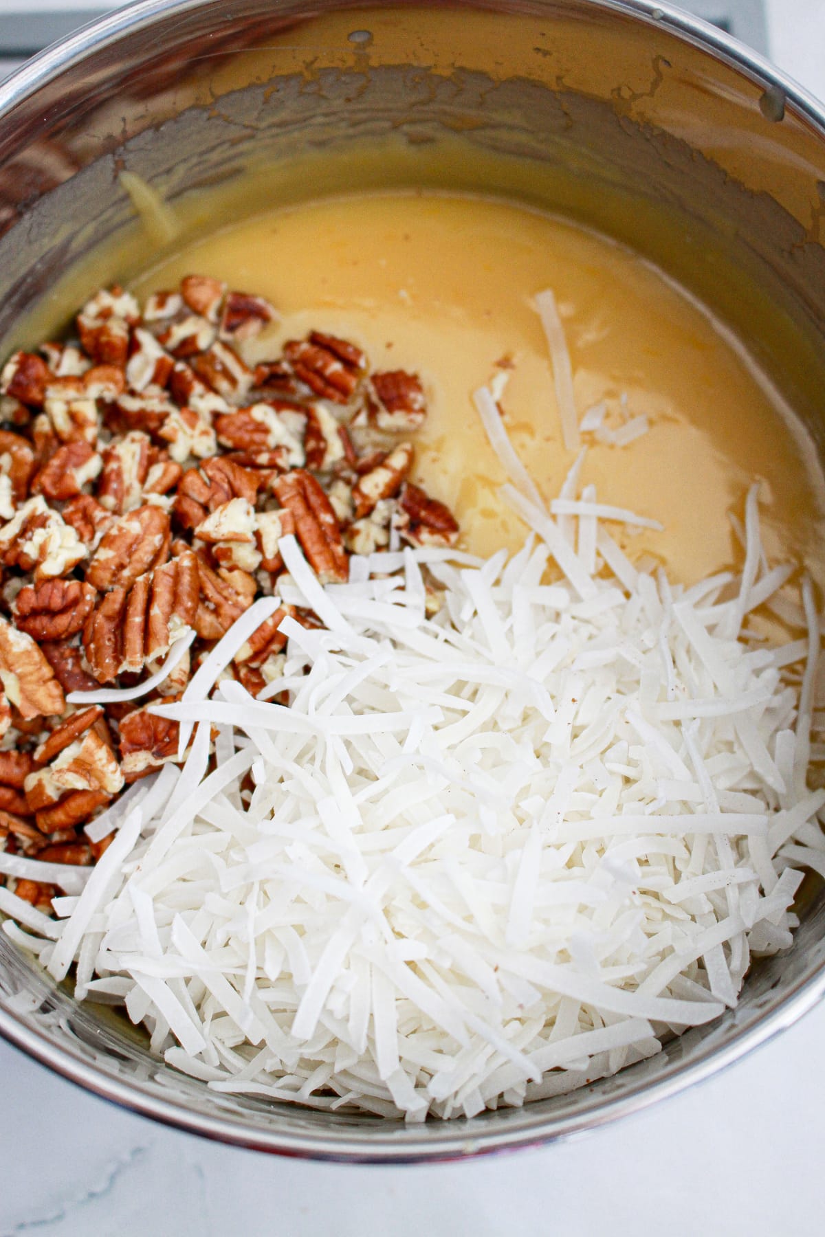 pecans and coconut in saucepan with topping