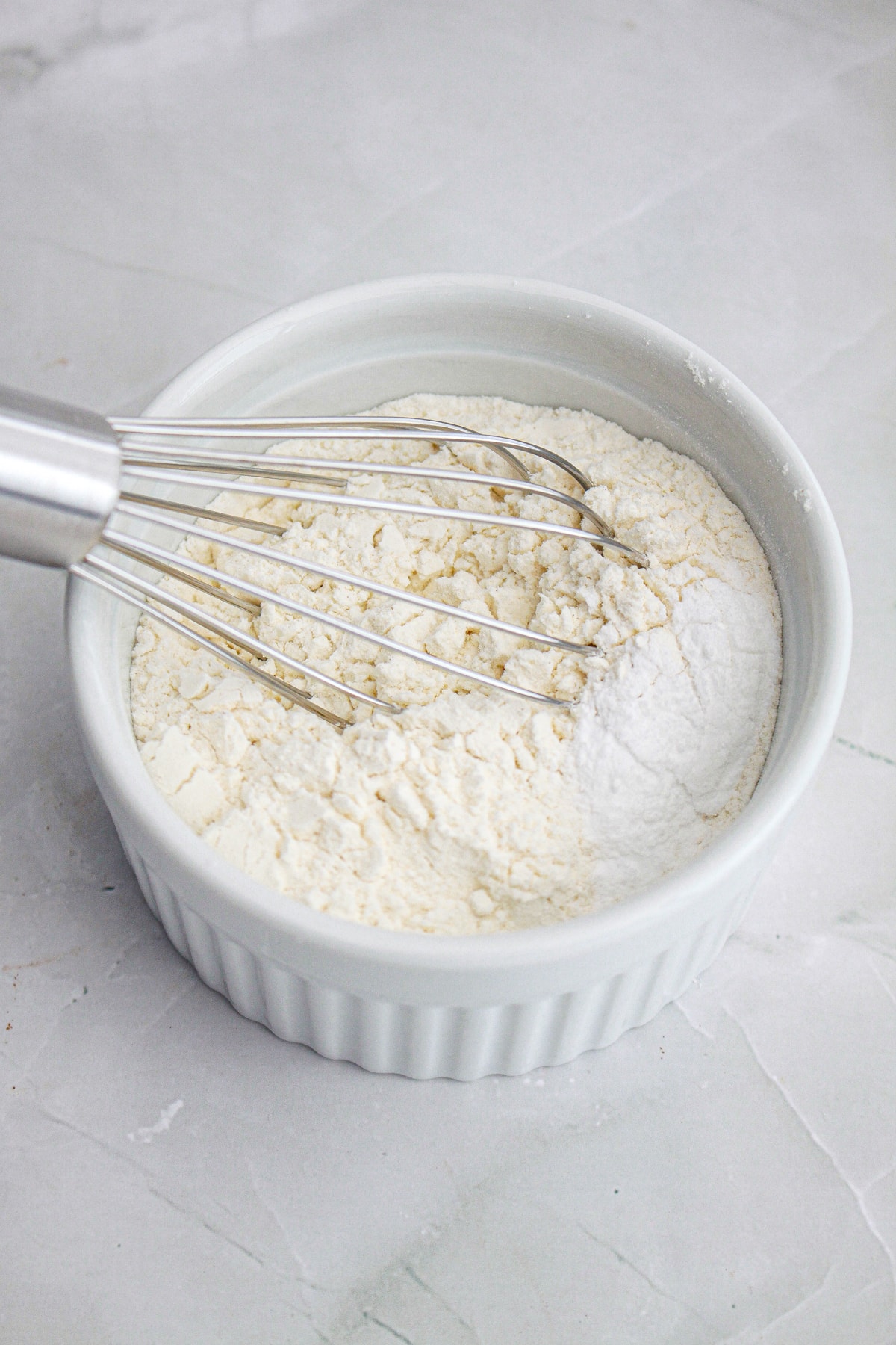 flour and dry ingredients in white bowl with whisk