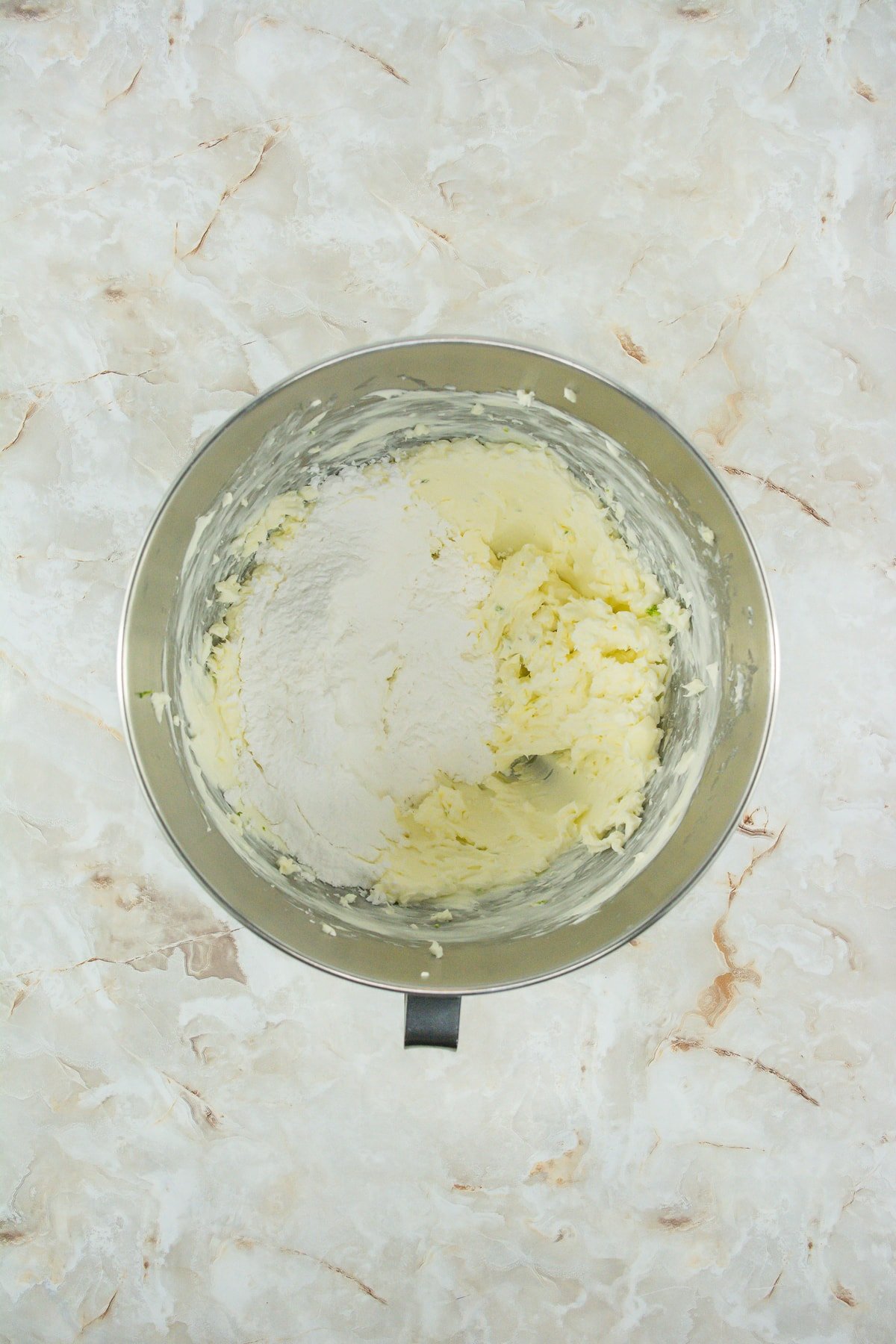 butter with powdered sugar for frosting in mixing bowl
