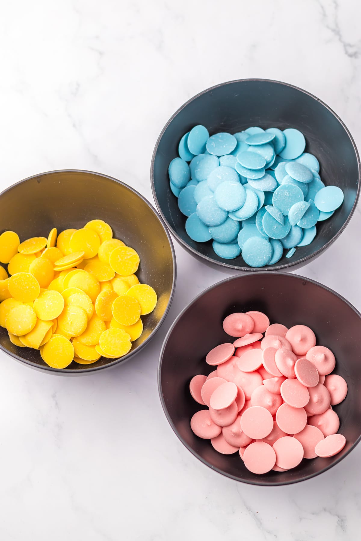 yellow, blue and pink chocolate candy wafers in bowls