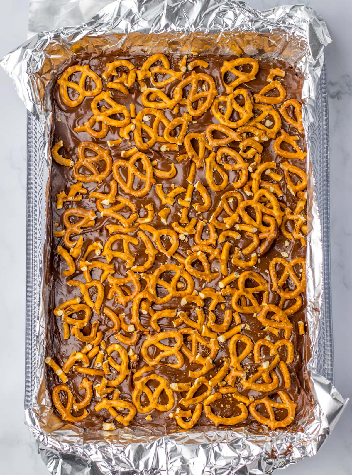 pretzels on top on melted chocolate on Peanut Butter Pretzel Bars