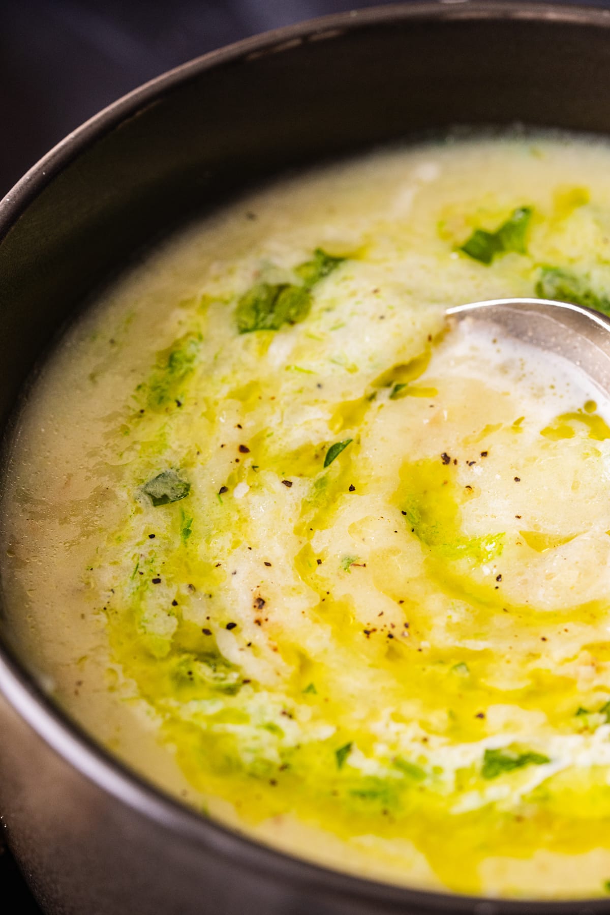 A bowl of potato leek soup with leek oil drizzled on top