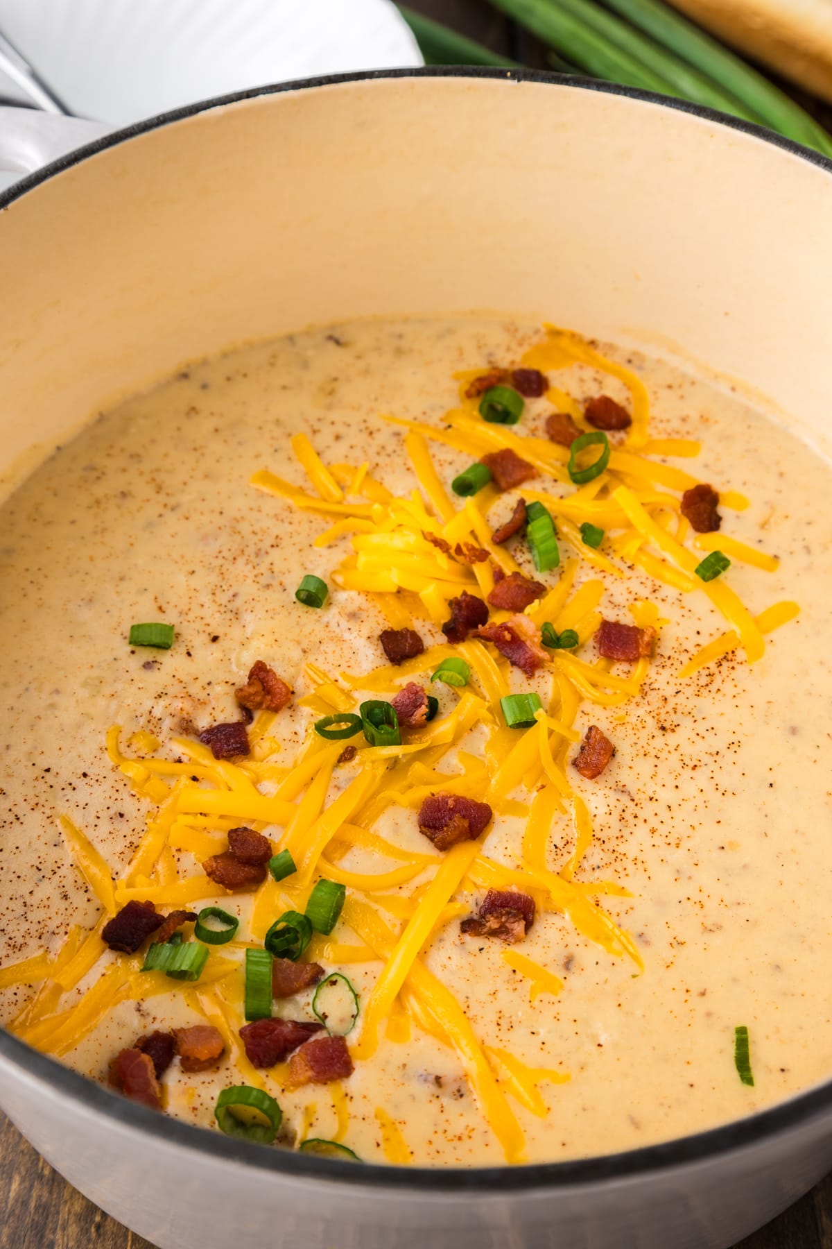A pot of potato soup topped with shredded cheese and bacon